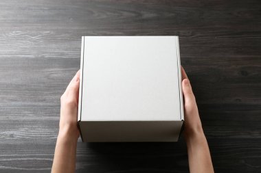 Karanlık ahşap arka planda boş karton kutulu bir kadın, yakın plan. Tasarım için model