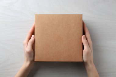 Beyaz ahşap arka planda boş karton kutulu kadın, üst manzara. Tasarım için model