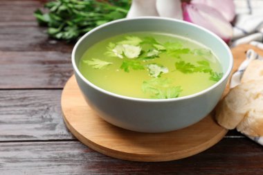 Lezzetli tavuk buğlonu kasede, ekmek ve malzemeler ahşap masada, yakın plan.