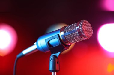 Mikrofon kırmızı arka planda bulanık ışıklarla duruyor. Bokeh etkisi