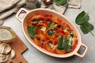 Lezzetli koni makarnası ricotta peyniri, ıspanak ve domates sosu ile gri dokuma masasında, düz yatıyordu.
