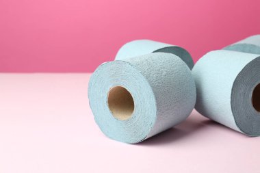 Pembe arka planda mavi tuvalet kağıdı ruloları. Metin için boşluk