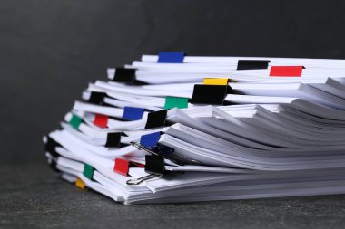 Koyu desenli masa üzerinde kağıt kağıtları olan renkli cilt ataçları, yakın plan