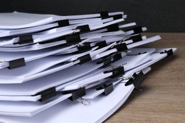 Koyu arkaplan ile ahşap masa üzerinde kağıt sayfaları ile cilt klipsleri, yakın çekim