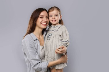 Mutlu anne portresi ve gri arka planda küçük tatlı kızı.