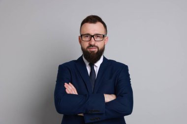 Gri arka planda takım elbiseli yakışıklı sakallı adam.