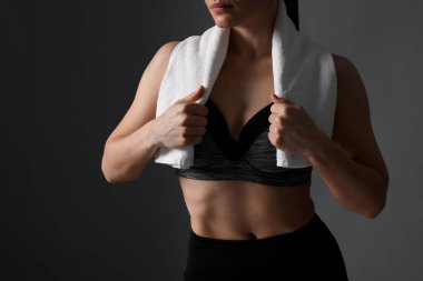 Koyu gri arka planda terry havlusu olan sportif kadın, yakın plan.