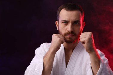 Renkli ışıklar içinde karate dövüşçüsü ve siyah arka planda duman. Metin için boşluk
