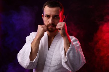 Renkli ışıklar içinde karate dövüşçüsü ve siyah arka planda duman