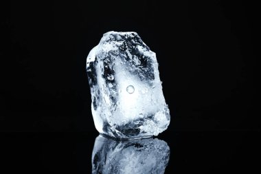 Siyah ayna yüzeyinde berrak buz parçası