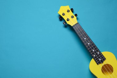 Açık mavi arka planda bir ukulele, üst manzara. Metin için boşluk