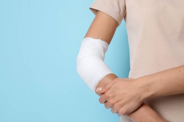 Dirseğinde yara bandı olan kadın açık mavi arka planda, yakın plan. Metin için boşluk