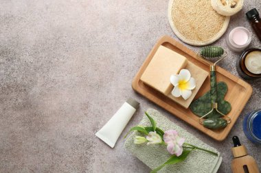 Farklı vücut bakım ürünleri, malzeme ve çiçekler gri masada, düz yerde. Metin için boşluk