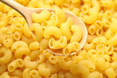 Arka plan olarak çiğ boynuzlar makarna ve kaşık, üst görünüm