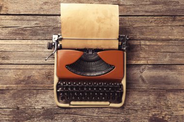 Tahta masasında kağıt olan eski tip daktilo, üst manzara.