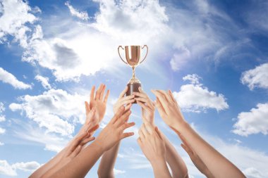 Altın kupa tutan kadın ve gökyüzüne uzanan insanlar.