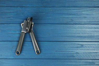 Mavi ahşap masada bir konserve açacağı, üst manzara. Metin için boşluk