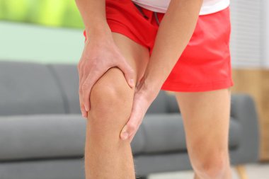 Genç adam closeup evde, diz ağrısı muzdarip