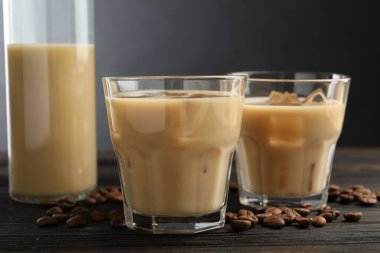 Bardakta kremalı kahve likörü ve ahşap masada fasulye, yakın plan.