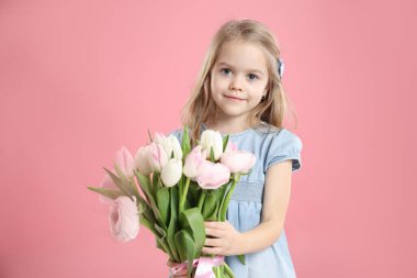 Pembe arka planda bir buket güzel bahar çiçeğiyle sevimli küçük bir kız.