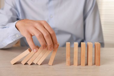 Ahşap blokların masada düşmesini engelleyen adam, yakın plan. Domino etkisi