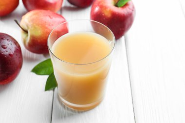 Elma suyunu bardakla tazelemek ve beyaz tahta masada meyveler, yakın plan. Metin için boşluk