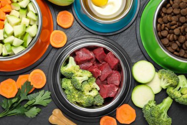 Doğal ve kuru evcil hayvan mamaları. Koyu dokulu masalardaki ürünler arasında beslenme kaselerinde.