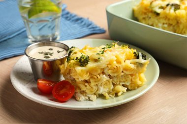 Tahta masada servis edilen peynirli ve brokolili makarna güveci.