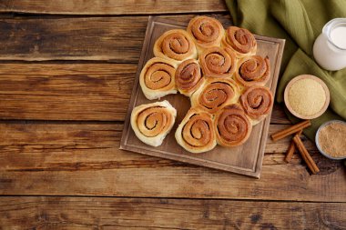Taze pişmiş tarçınlı rulo, süt ve baharatlar ahşap masada, düz yatak. Metin için boşluk