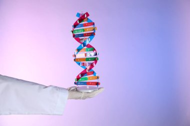 Renk arkaplanı üzerinde DNA yapı modeline sahip bilim adamı, yakın plan