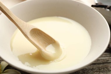 Lezzetli vanilyalı yoğurtlu sütü ahşap masadaki kaşıkla yakın plan çekiyoruz.