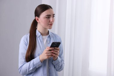 Stresli kadın, evdeki pencerenin yanındaki ruh sağlığı yardım hattını arıyor. Metin için boşluk