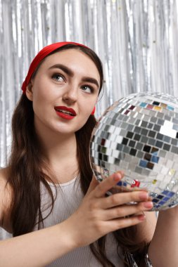 Gümüş folyo perdeye karşı disko topuyla güzel bir genç kadının portresi