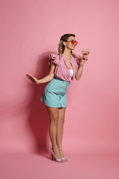 Happy pin-up woman with cocktail on pink background