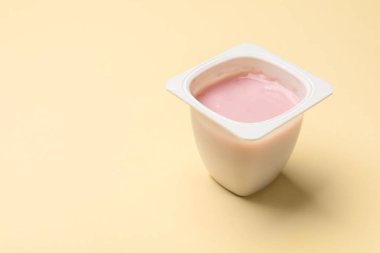 Bej arka planda plastik bardakta lezzetli yoğurt, yakın plan. Metin için boşluk
