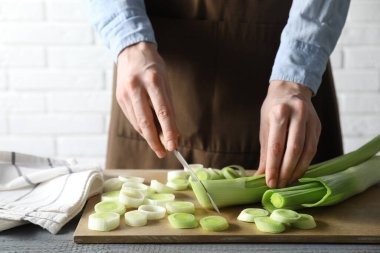 Gri ahşap masada pırasa kesen kadın, yakın plan.