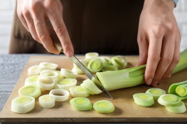 Gri ahşap masada pırasa kesen kadın, yakın plan.