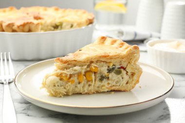 Beyaz mermer masada tavuk ve sebzeli lezzetli ev yapımı turta, yakın plan.