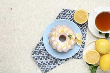 Limon aromalı lezzetli pasta, pudra şekeri, nane, çay ve narenciye meyveleri açık dokulu masa, düz yatak. Metin için boşluk