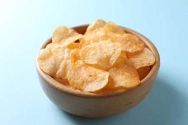 Açık mavi arka planda, kasede patates cipsi, yakın plan.
