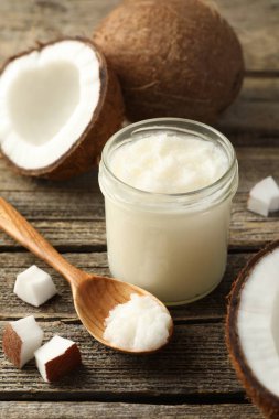 Cam kavanozda organik hindistan cevizi pişirme yağı, kaşık ve ahşap masada taze meyve.