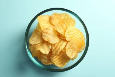 Açık mavi arka planda leziz patates cipsi, üst manzara.