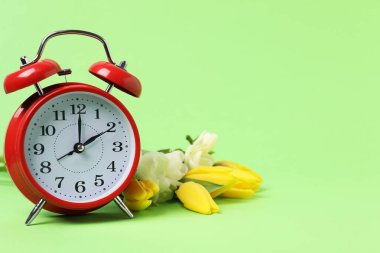 Bahar geldi. Alarm saati ve yeşil arkaplanda güzel çiçekler, metin için boşluk
