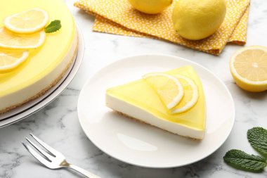 Lezzetli limonlu cheesecake, çatal, nane ve narenciye meyveleri beyaz mermer masada, yakın plan.