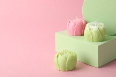 Pembe arka planda güzel çiçek şekilli mumlar. Metin için boşluk