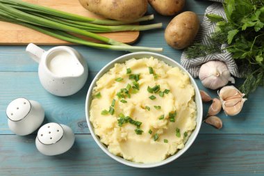 Açık mavi ahşap masada servis edilen yeşil soğanlı leziz patates püresi.