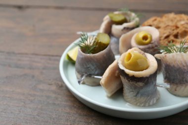 Zeytinli, turşulu ve ahşap masada dereotlu ringa dürümleri. Yakın plan. Metin için boşluk