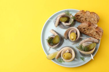 Sarı masada zeytinli, turşulu, dereotlu ve ekmekli lezzetli ringa dürümleri. Metin için boşluk