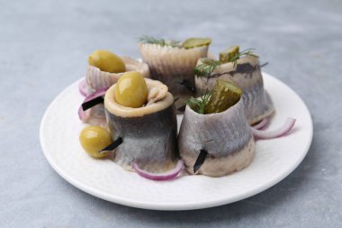 Gri masada zeytinli, turşulu, dereotlu ve soğanlı lezzetli ringa dürümleri.