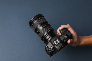 Koyu gri arka planda profesyonel kamerası olan bir fotoğrafçı. Metin için boşluk
